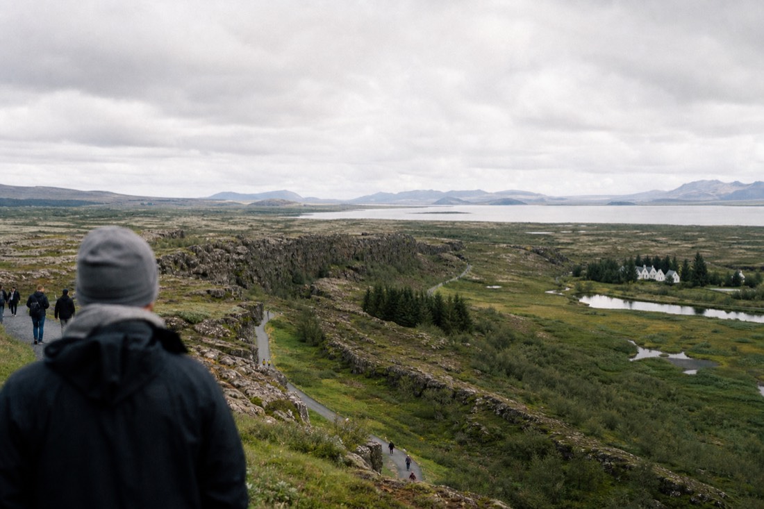 Wide view over the Þingvellir rift valley from the Hakið viewpoint, cliffs dropping to the green valley floor and lake beyond