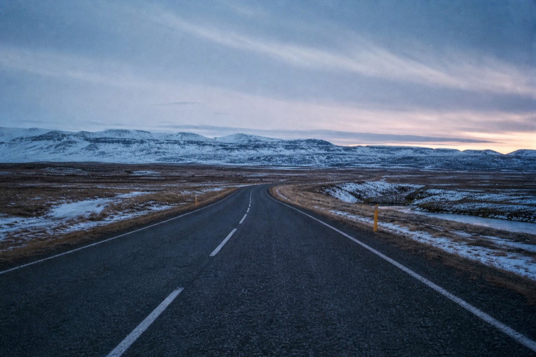 Empty paved Route 35 near Faxi waterfall stretching toward distant hills at winter dusk