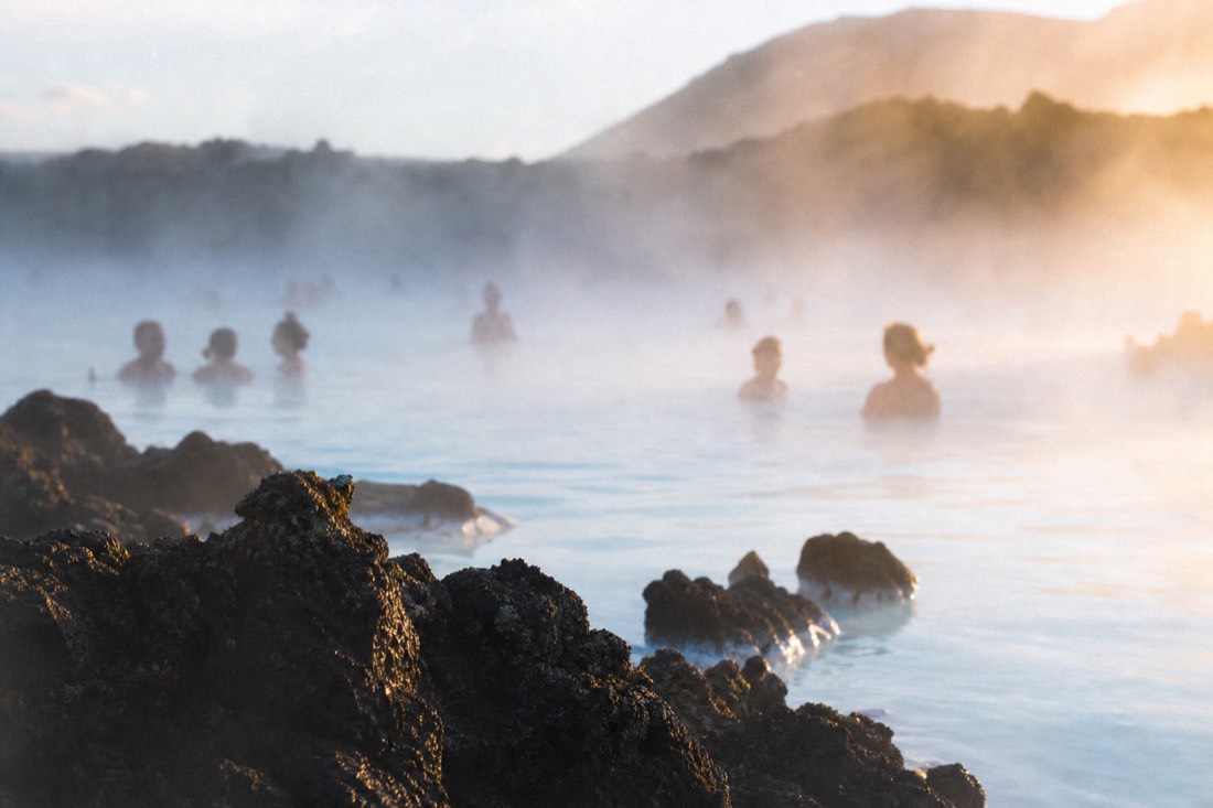 Milky blue geothermal water steaming against black lava rock at the Blue Lagoon in evening light